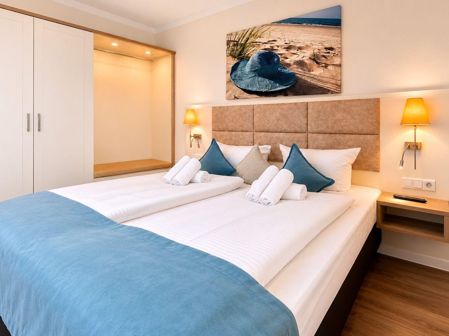 Zimmer mit Sofa, Fenster, Wandbild und Regal mit Dekorationsgegenständen.