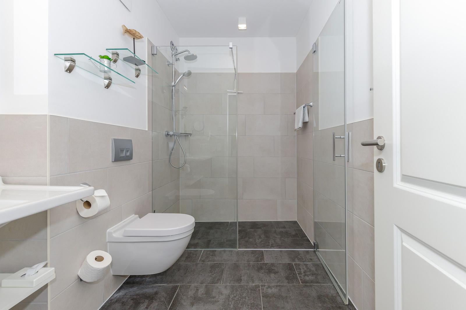 Badezimmer mit Dusche, Toilette und Waschbecken.