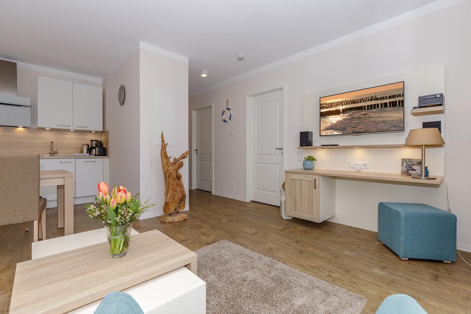 Wohnzimmer mit Küchenbereich, Fernseher und Holzboden