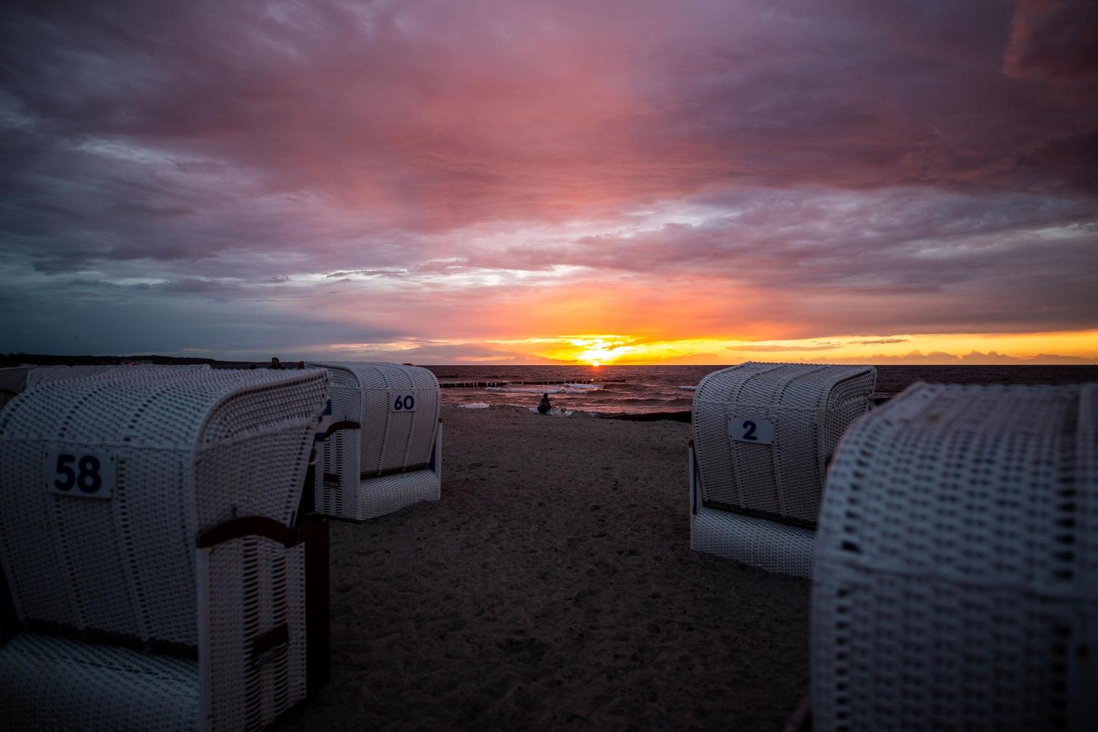 Strand mit Liegestühlen und Sonnenuntergang über dem Meer.