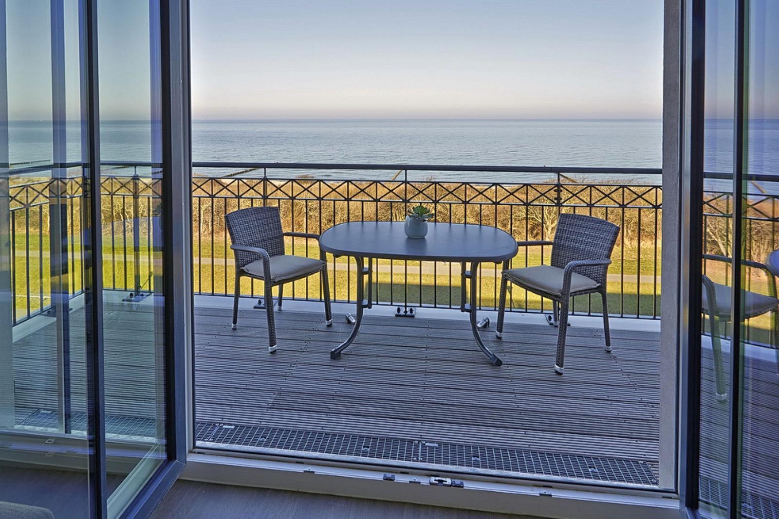 Terrasse mit Tisch und zwei Stühlen bietet Meerblick.