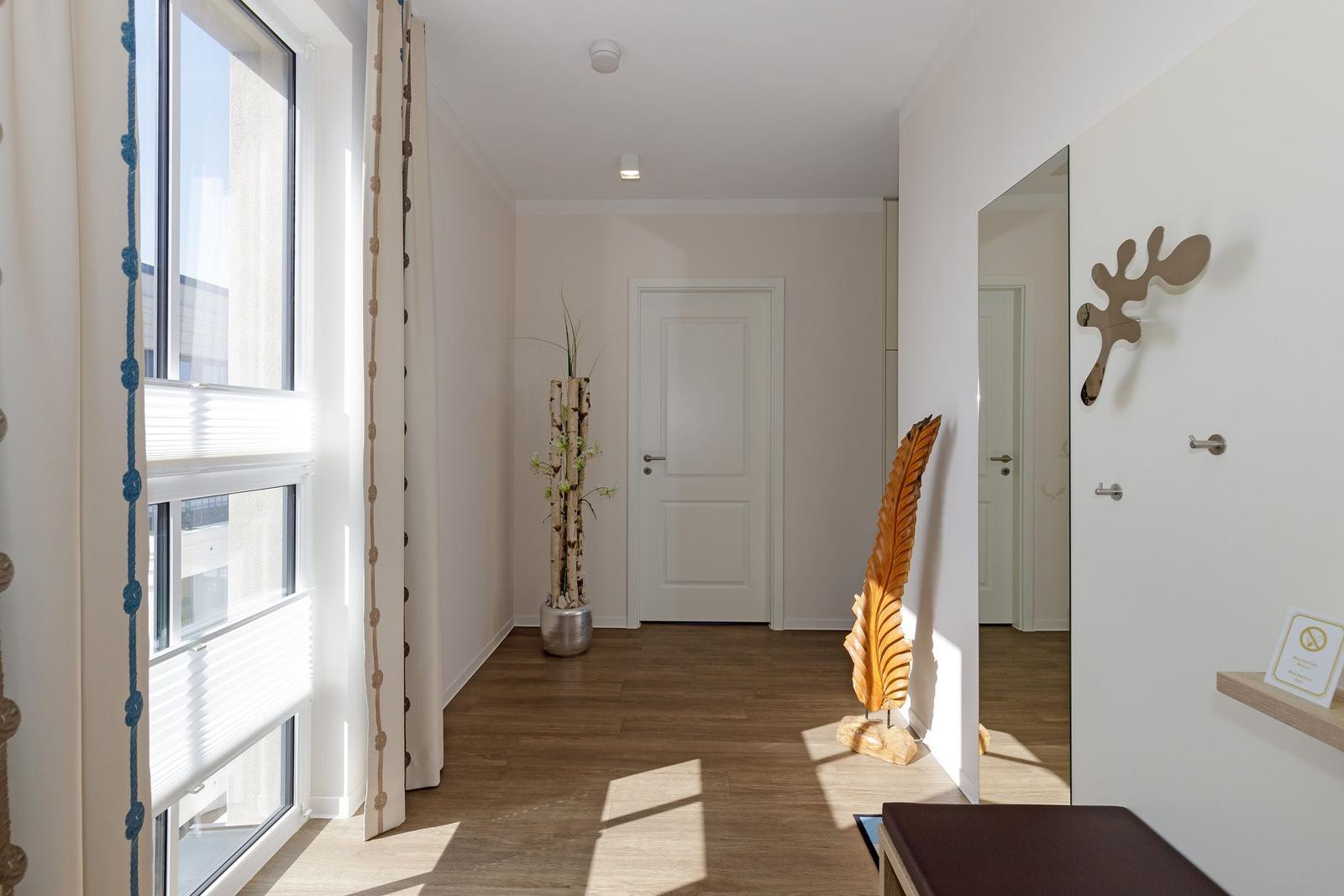 Halle mit Holzboden, Fenster, Spiegel und Dekorationsgegenständen