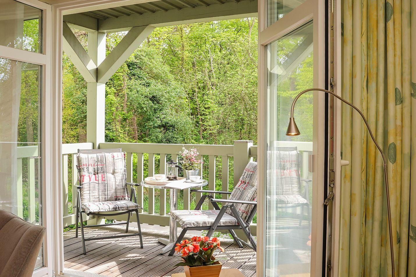 Terrasse mit zwei Stühlen, Tisch und Blick in den Wald.