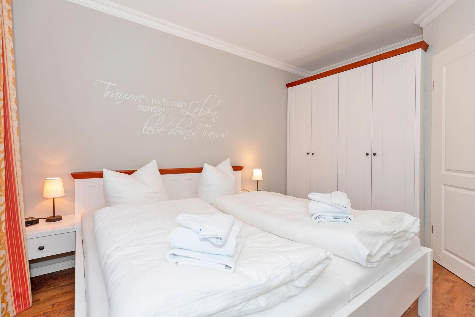 Schlafzimmer mit Doppelbett, Kleiderschrank und Wanddekoration.