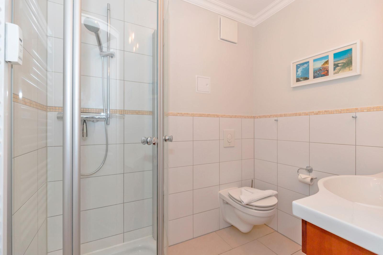 Badezimmer mit Dusche, Toilette und Waschbecken.