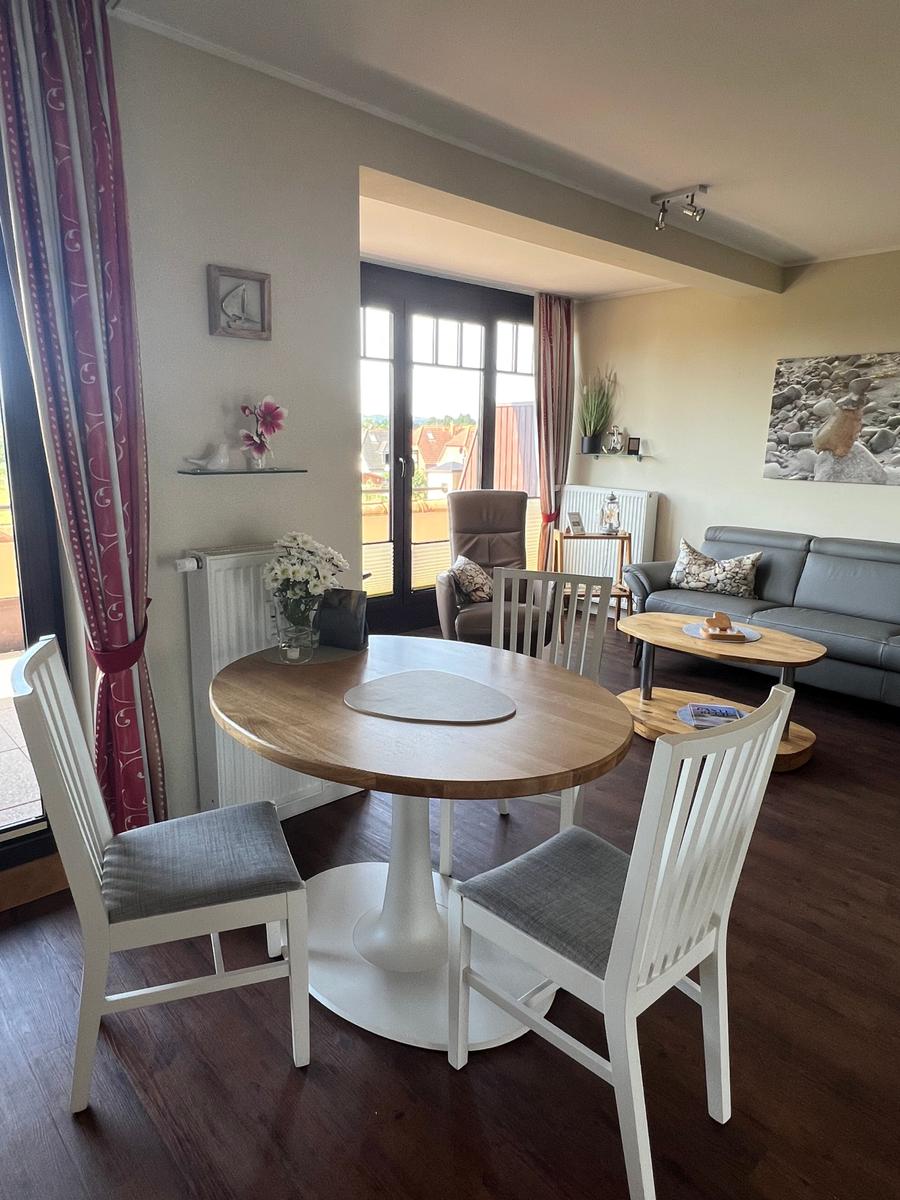 Essbereich mit runden Tisch und Stühlen. Wohnbereich mit Sofa und Couchtisch.