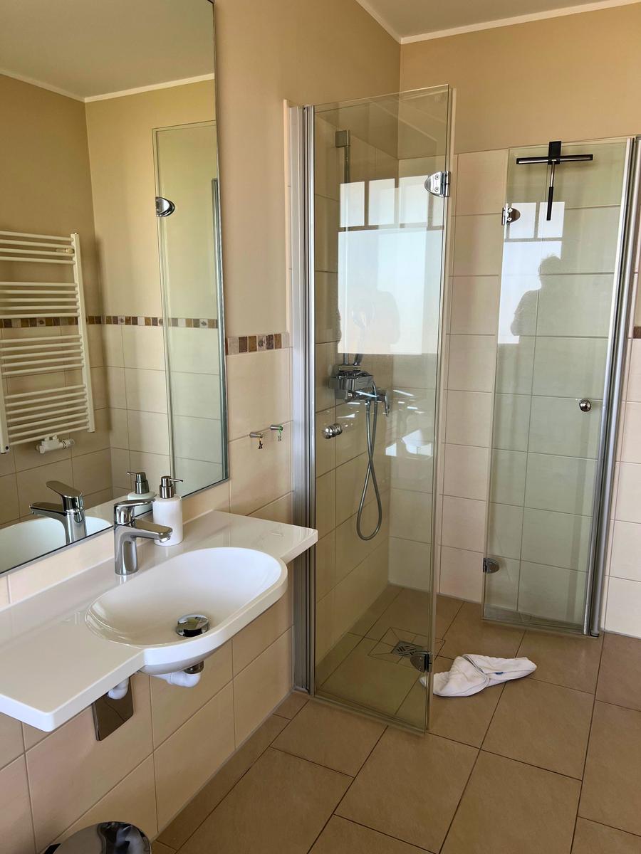 Badezimmer mit Dusche, Waschbecken und Spiegel