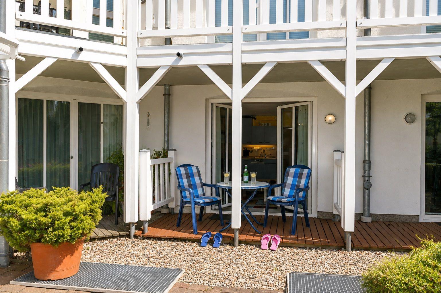 Haus mit weißem Balkon, Gartenbereich und rosa Bank im Vordergrund.