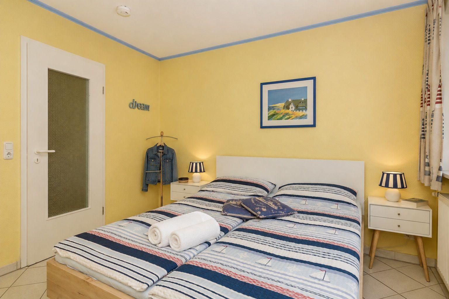 Schlafzimmer mit Bett, Fenster, TV und Schrank.