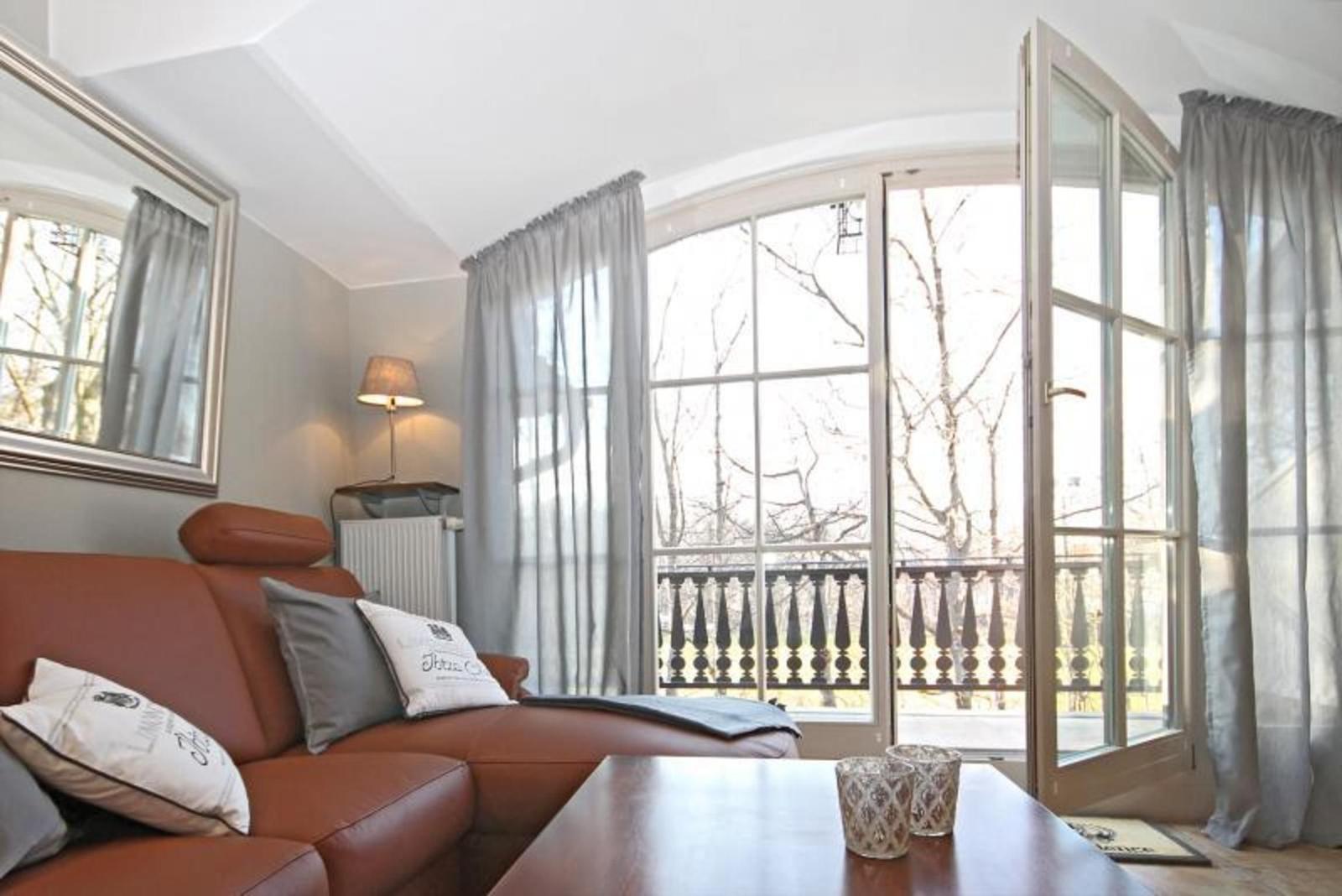 Ein Wohnzimmer mit braunem Sofa, Tisch und Fenster zur Terrasse.