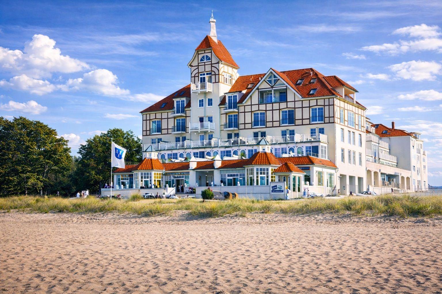 Strandnahe Villa mit rotem Dach und weißen Balkonen unter blauem Himmel.