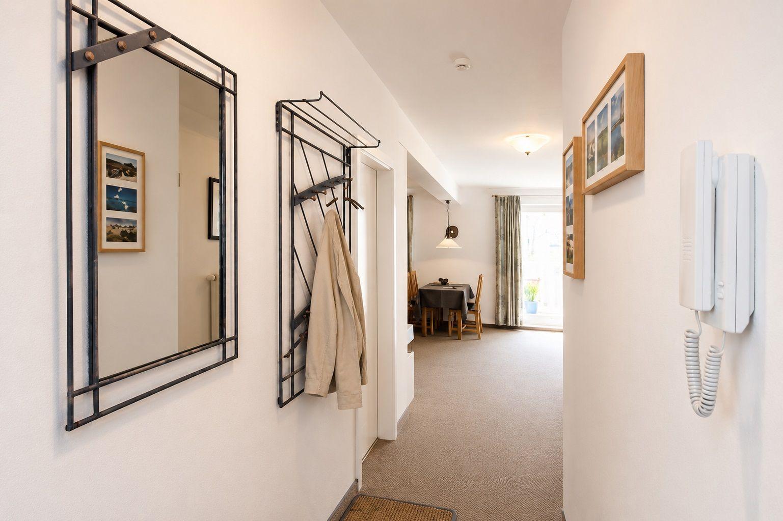 Flur mit Spiegel, Garderobe und Telefon. Blick in Esszimmer mit Tisch und Stühlen.