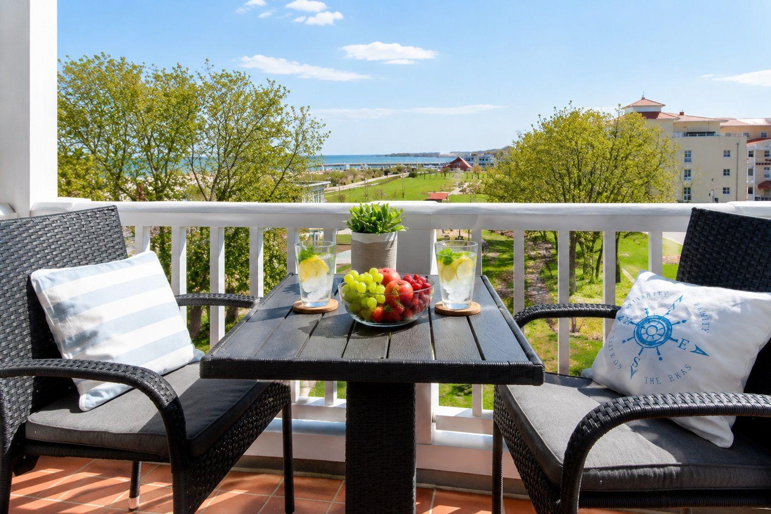Terrasse mit Tisch, zwei Stühlen und Blick auf Grünfläche und Wasser.