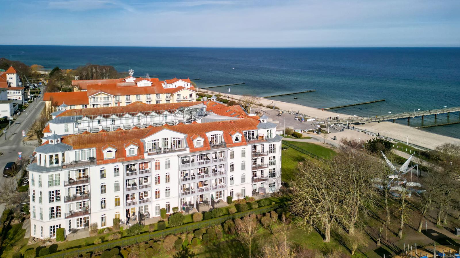 Großes Hotel mit rotem Dach und Balkonen direkt am Strand.