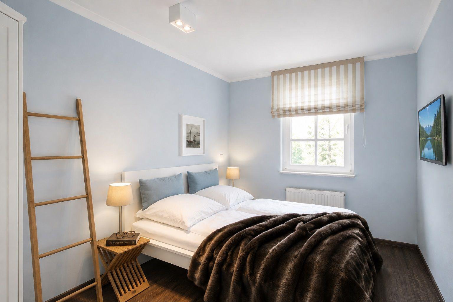 Schlafzimmer mit Bett, Fenster, Lampe und Holzleiter.