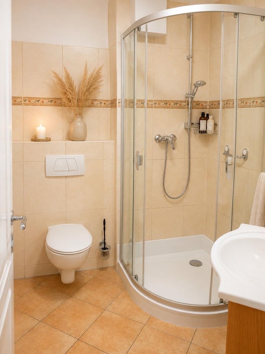 Bathroom with shower, toilet, and sink. Wall and floor tiles in beige.