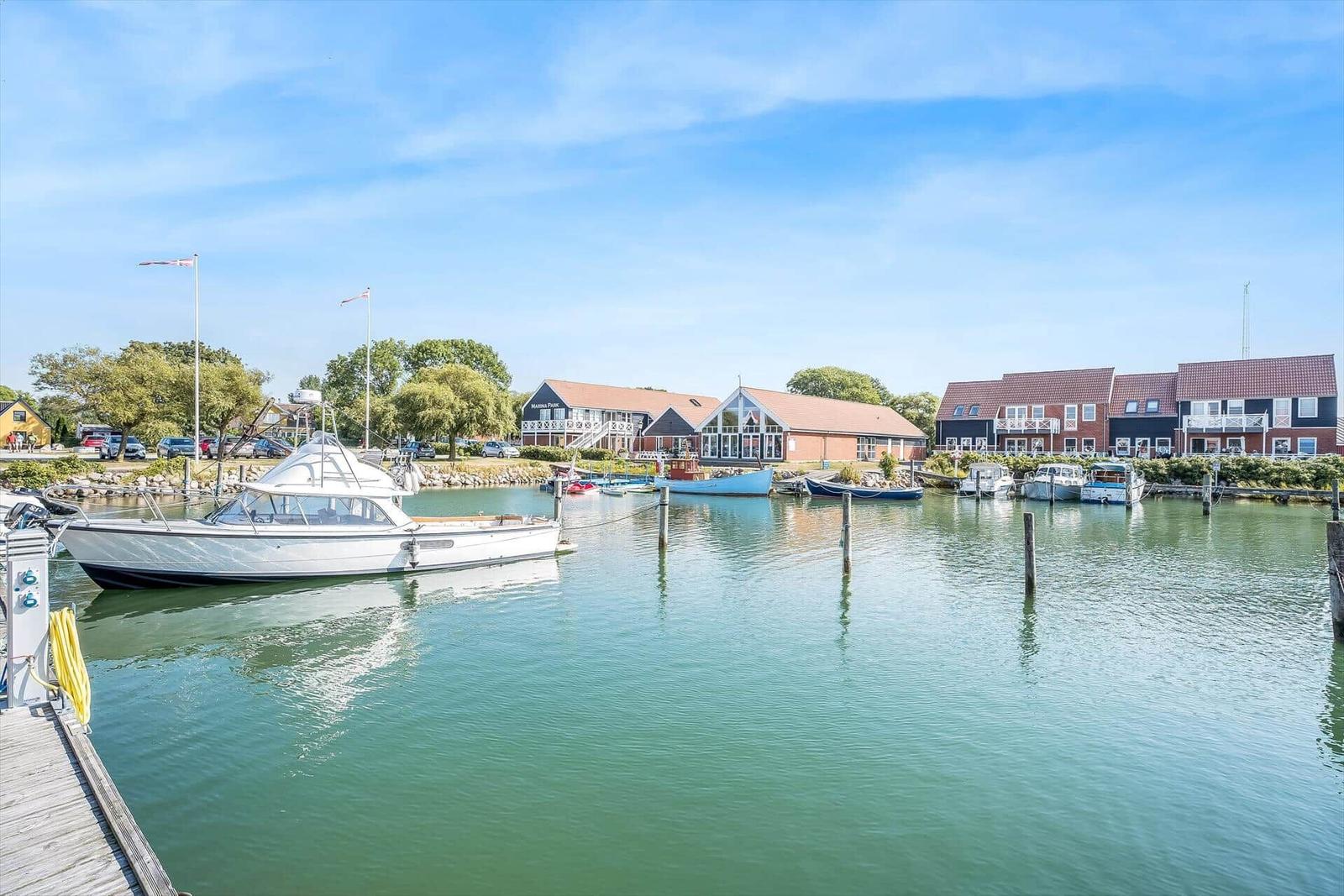 Houses by the harbor with boats and a dock. Green areas and clear view.