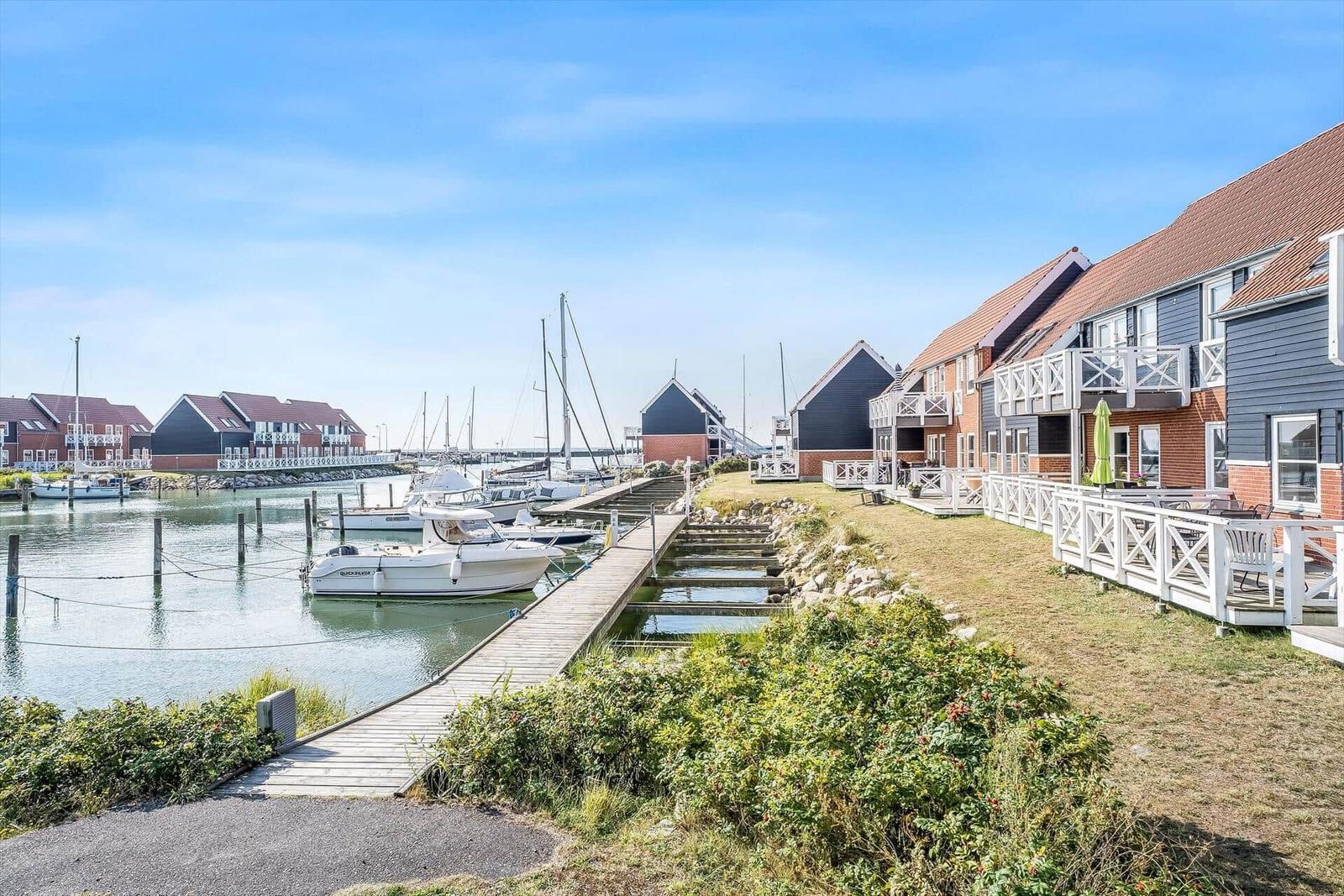Harbor with sailboat, parking spots, and view of the sea.