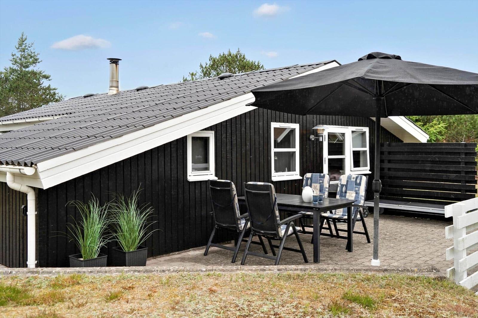 Two black wooden houses with white window frames and door. Number 64 on one house.