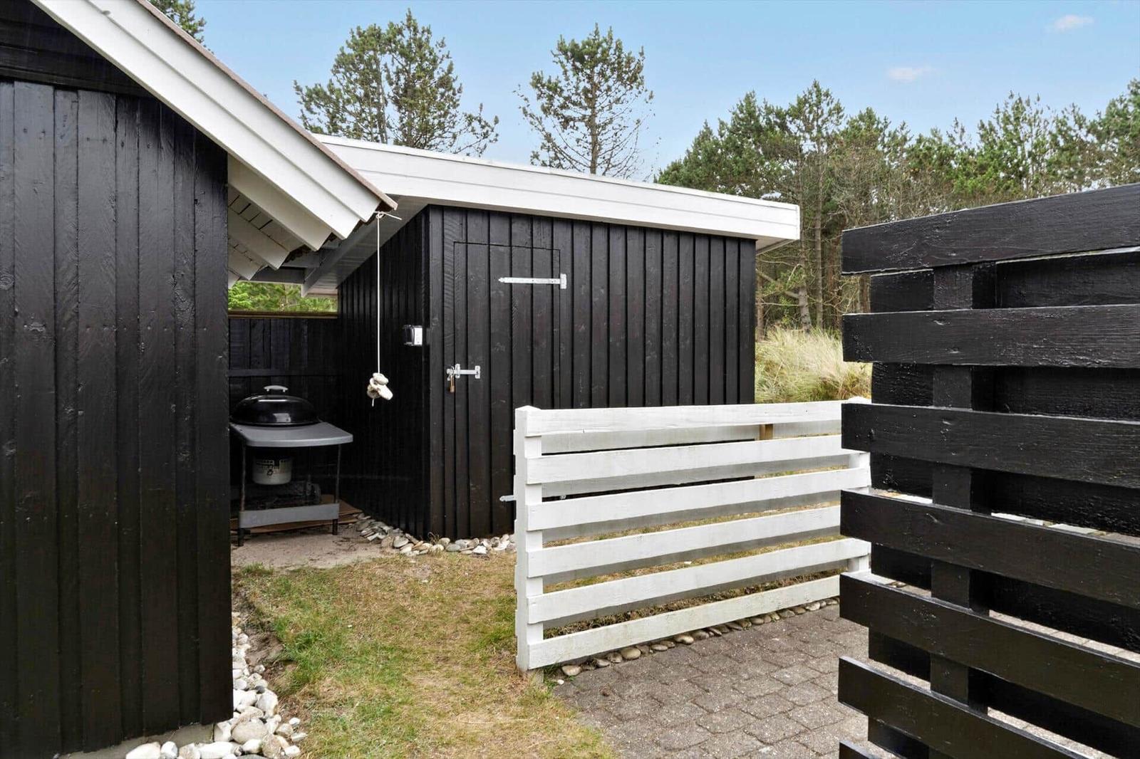 Black house with terrace, table, chairs, and umbrella.