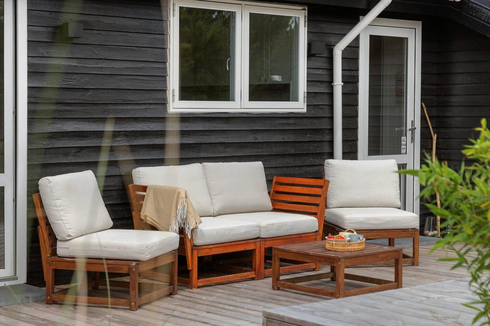 Terrace with table, chairs, umbrella, and grill. View of grassland and trees.