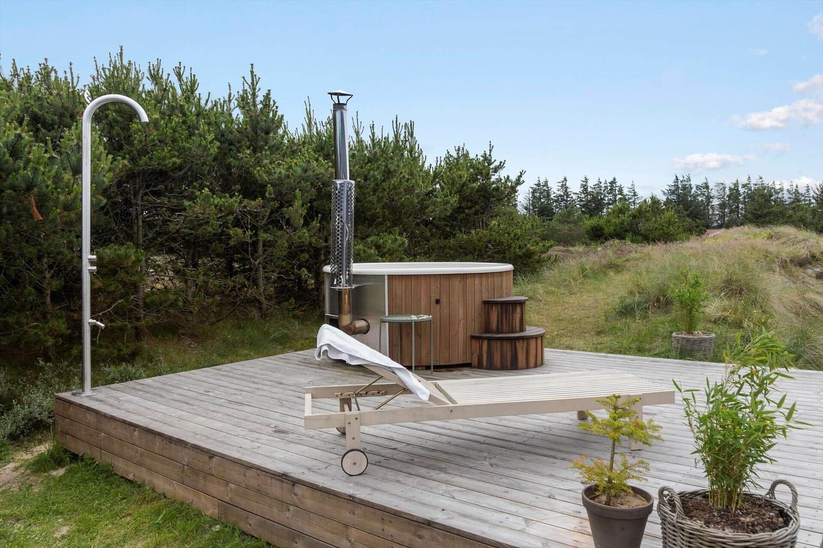 Terrace with table, chairs, umbrella, and grill. View of grassland and trees.