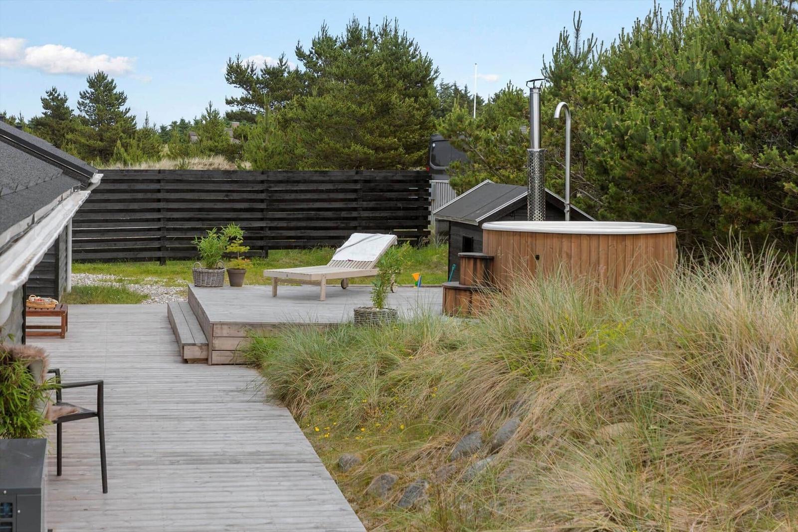 Terrace with table, chairs, and umbrella. Natural path through dune landscape.