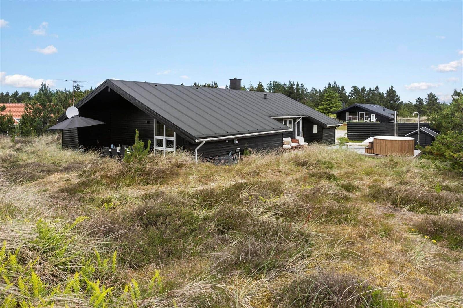 A small house in a hilly, grassy landscape with trees in the background.