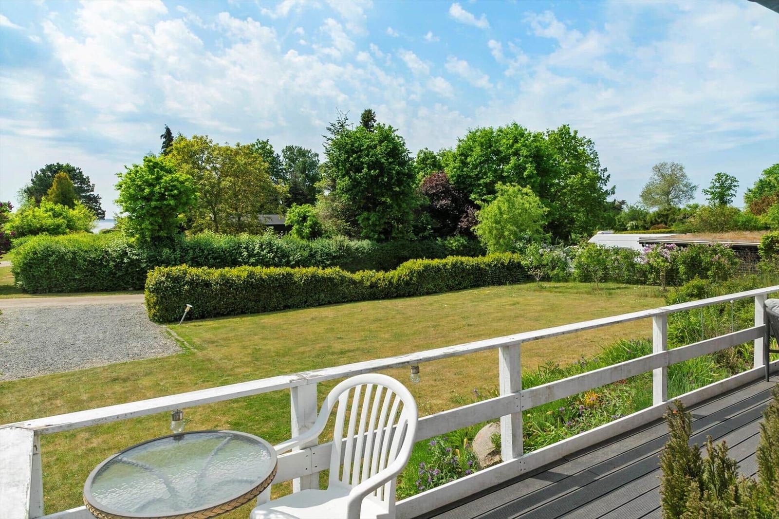 Deck with grill, seating, and view of green surroundings.