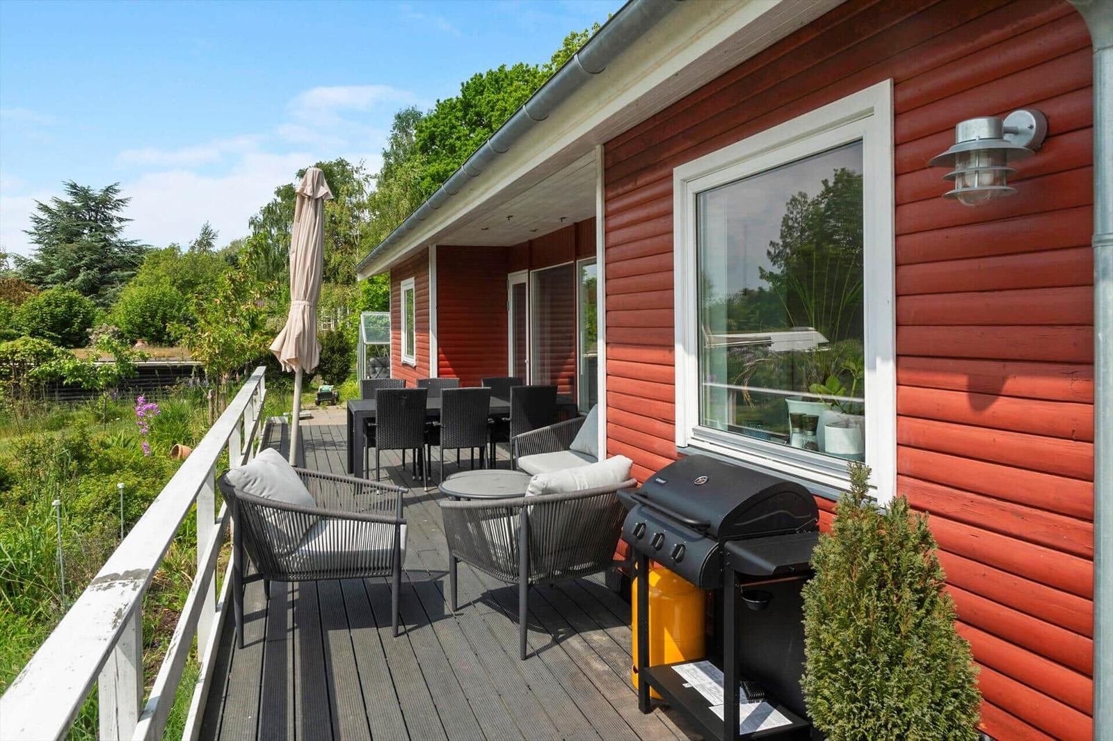 Terrace with seating group, table, and umbrella. View of green landscape.