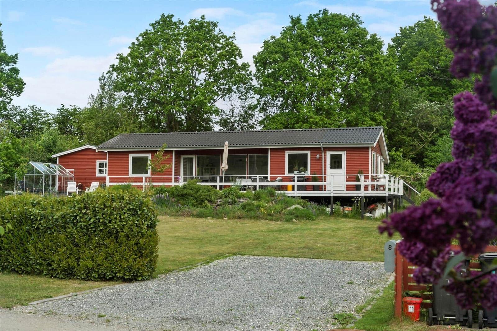 Red house with terrace, grill, and greenhouse in the garden.