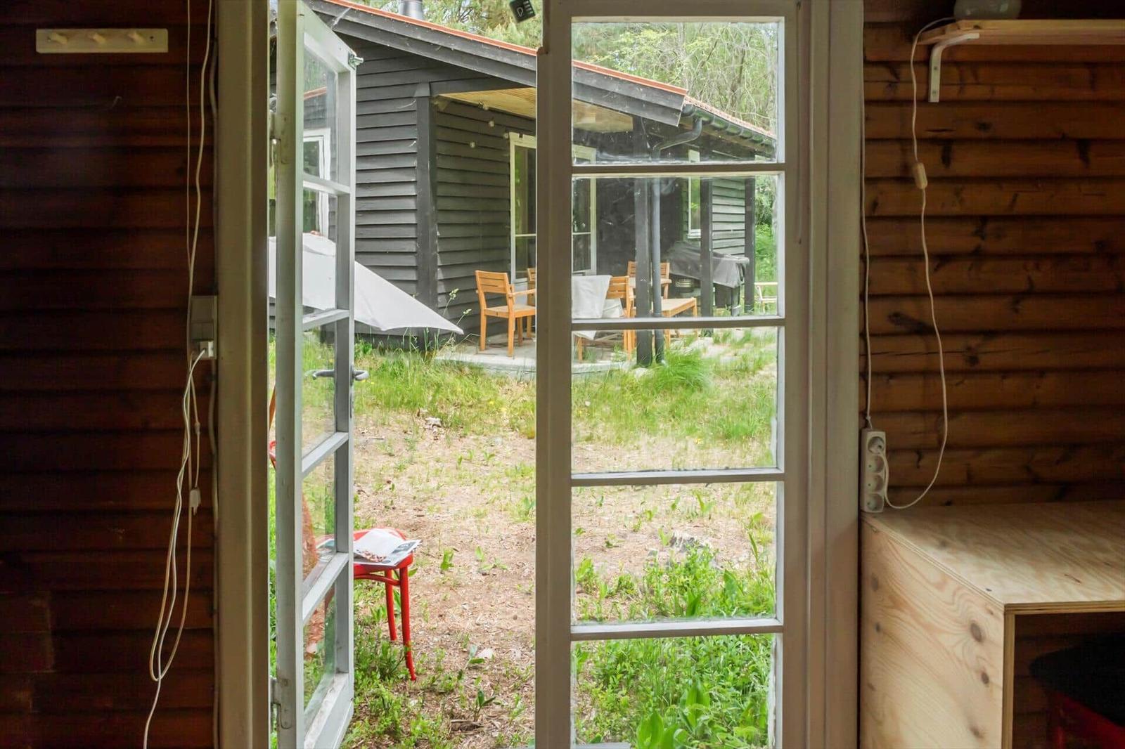 Wood-paneled accommodation with bed, sofa, table and chairs, window, and ceiling lights.