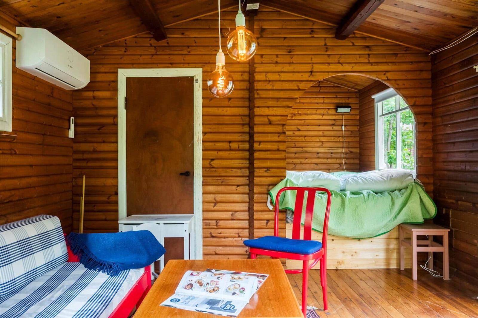 A living room with wooden walls, a red sofa, and a red chair.