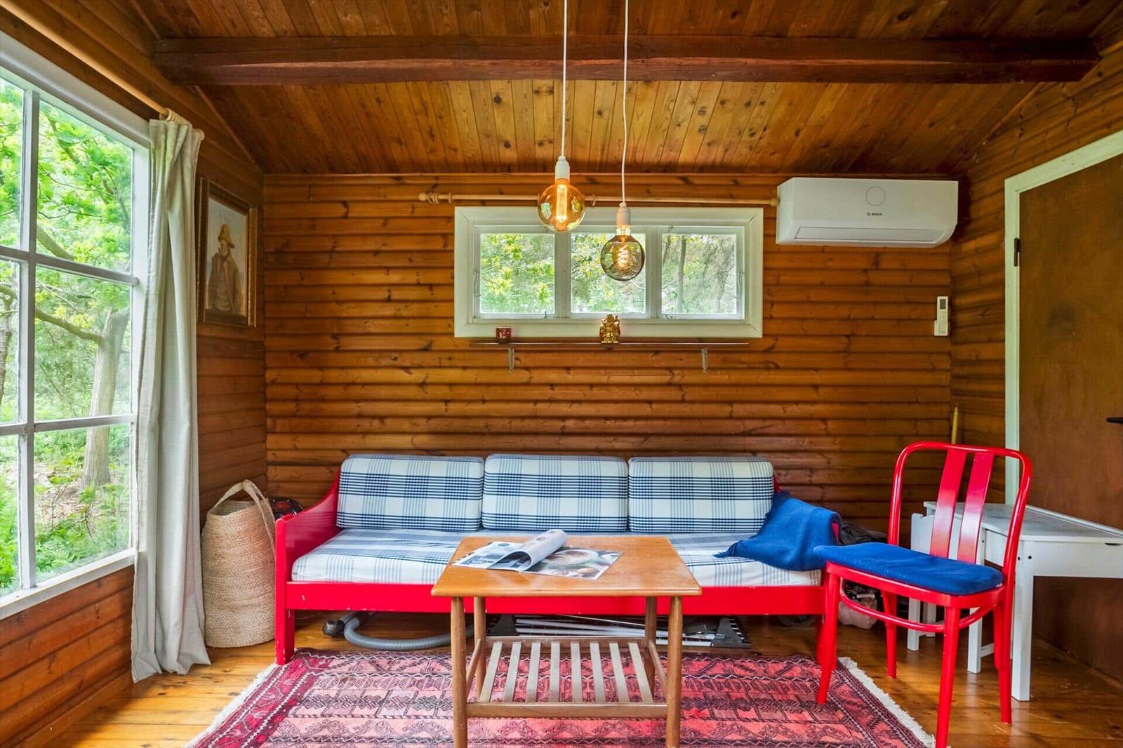 Bedroom with wooden walls, bed, TV, and view of garden.