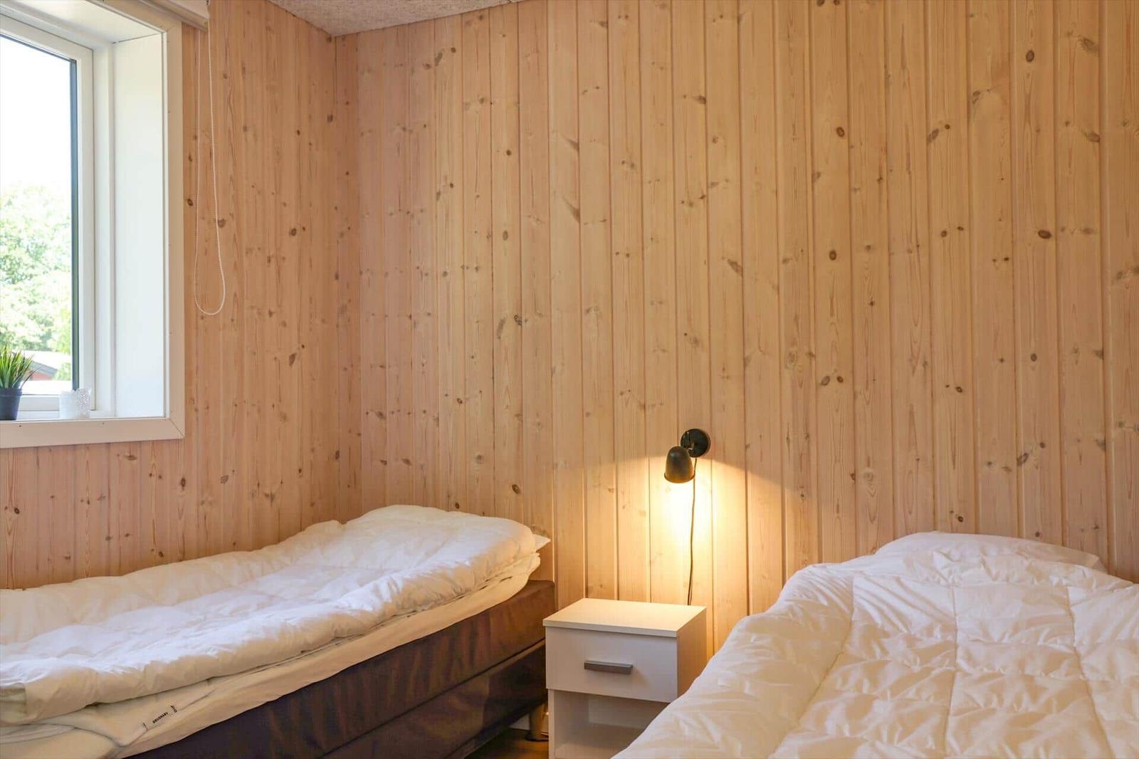 Bedroom with wooden walls, bed, and window with view of greenery.