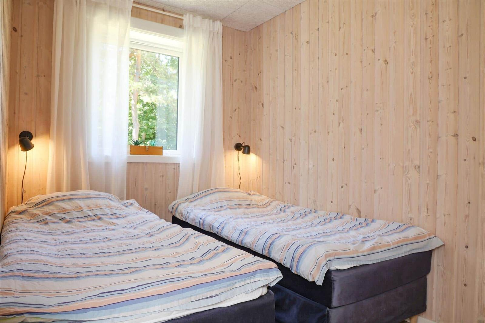 Bedroom with wooden walls, wardrobe, and view into bathroom and living area.