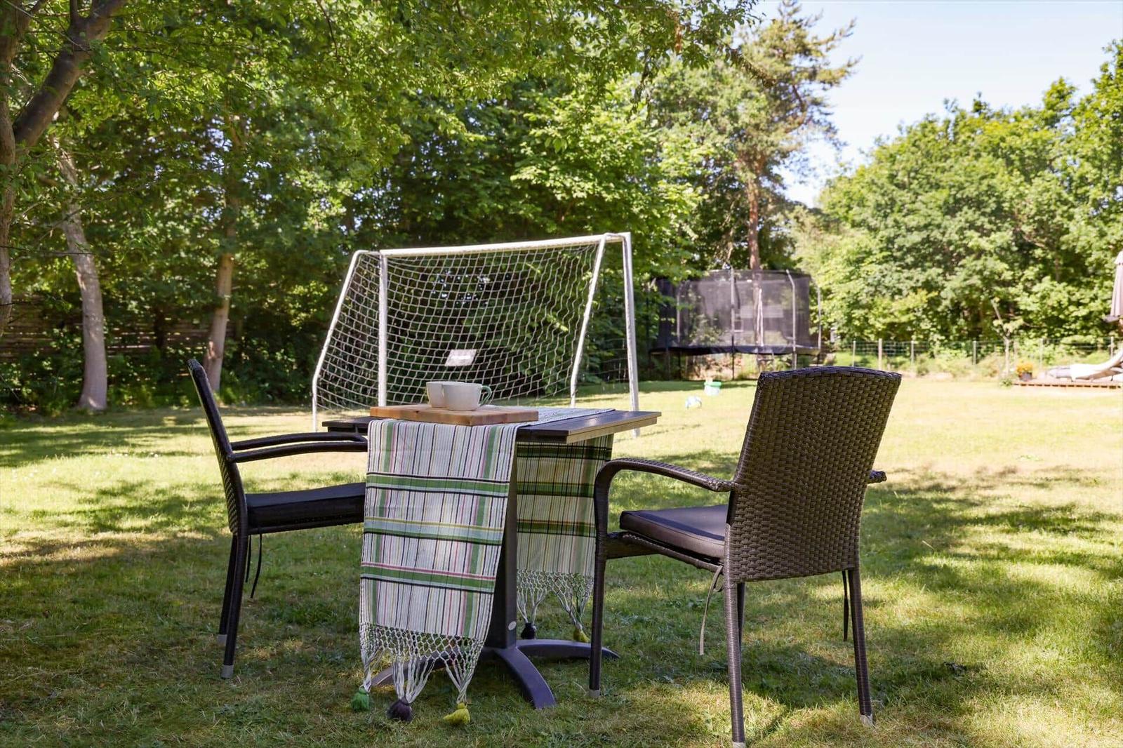 Backyard with lounge chair, umbrella, and hanging chair in front of a house.