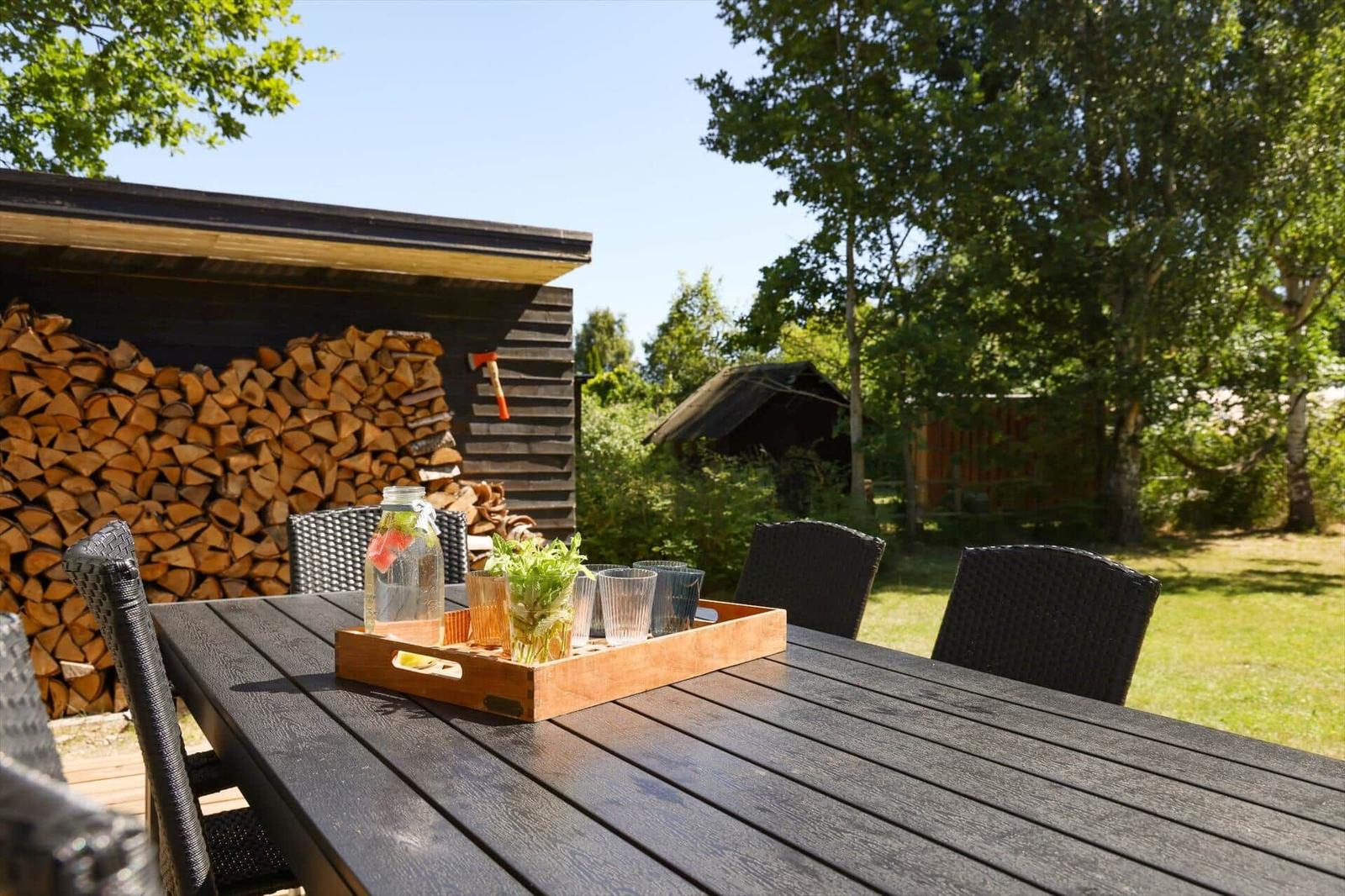 Deck with seating group and wooden planks. Background: green lawn and trees.