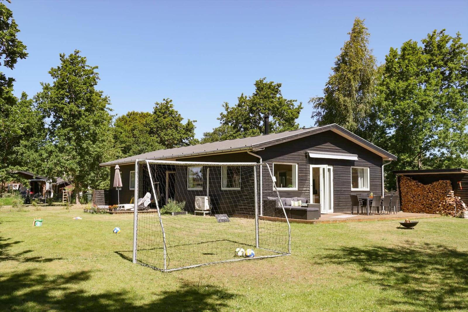 Deck with seating, grill area, and view of a green garden.