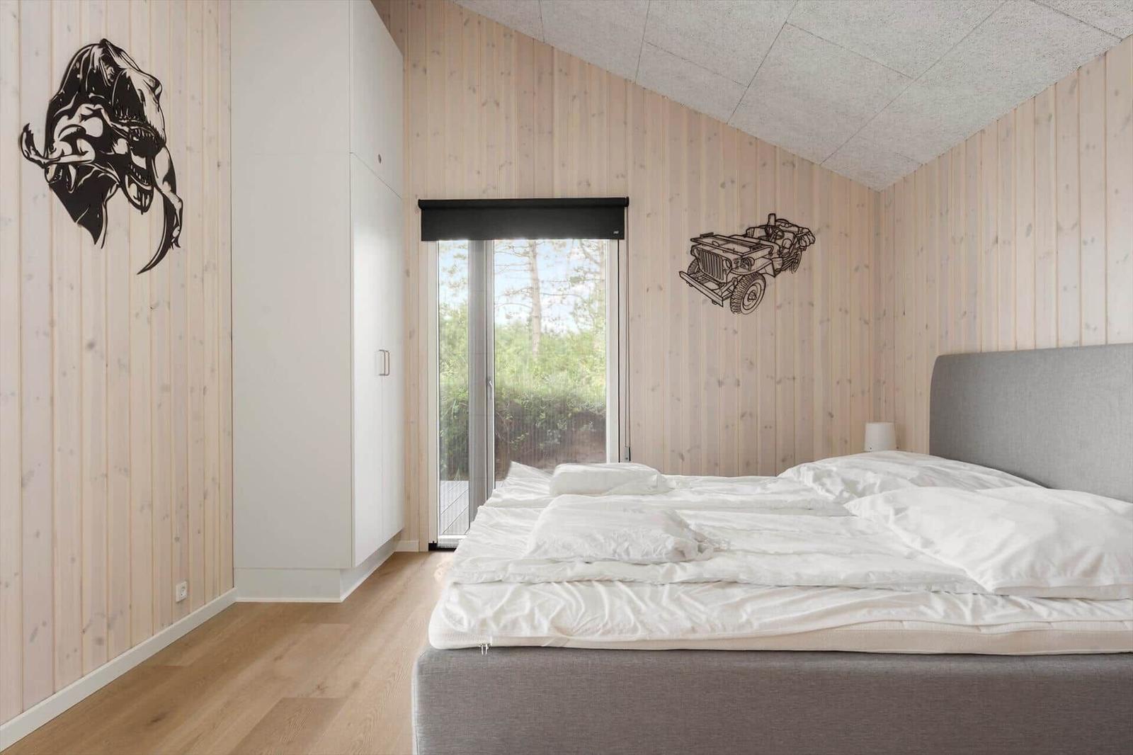 A room with dining table, sofa, and fireplace. Large windows offer views of nature.