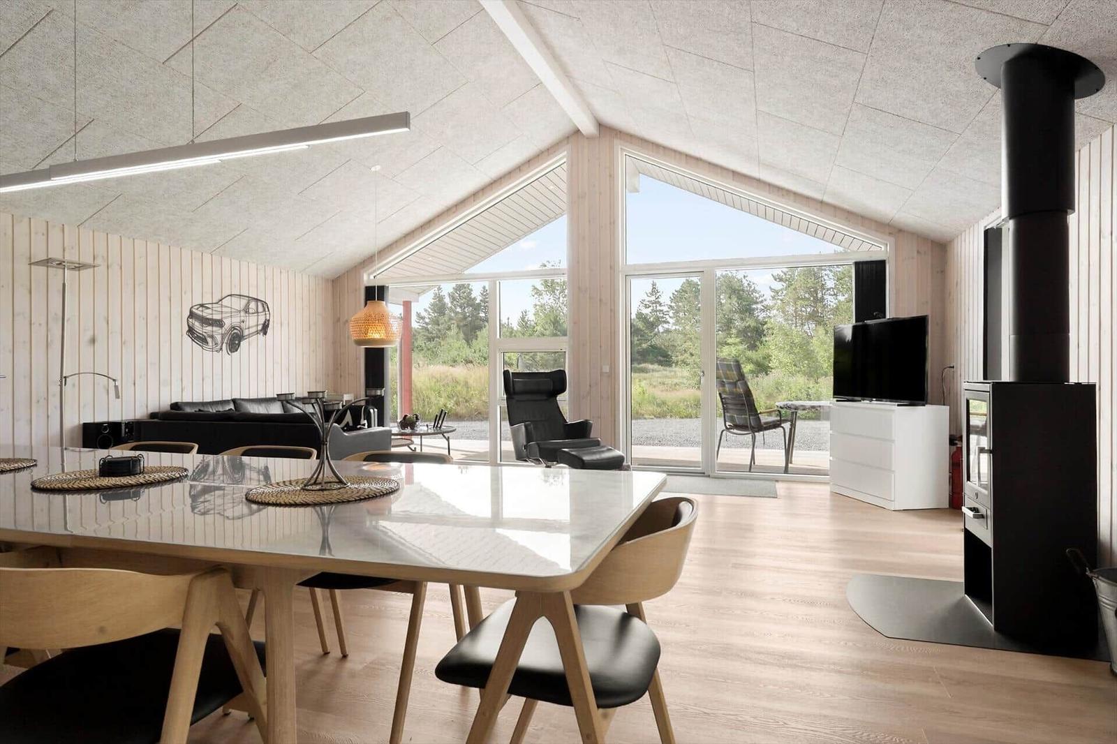 Dining room with wooden walls, dining table, and wood stove. Wall art of a vehicle.