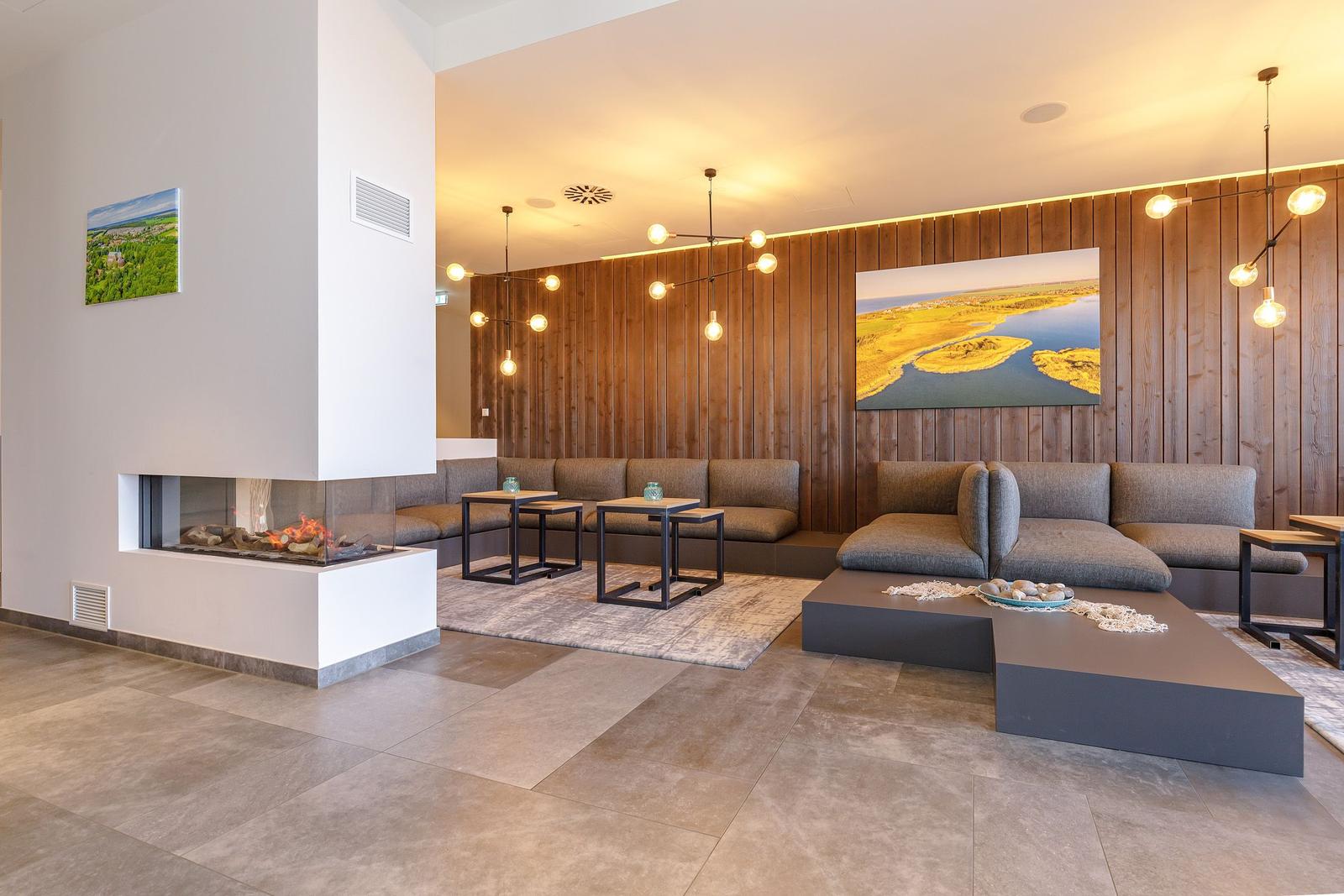 Wohnbereich mit Sofa, Kamin und Holzwand. Moderne Beleuchtung und Wandbilder.