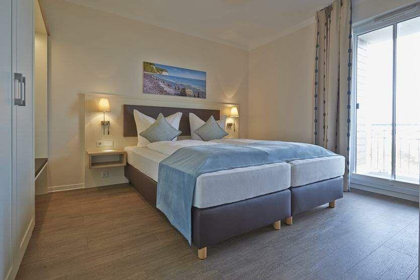 Schlafzimmer mit Doppelbett, Schrank und Balkonzugang.