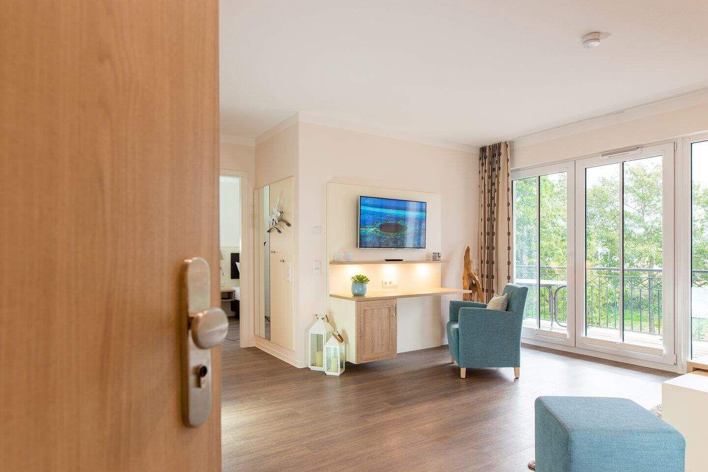 Wohnzimmer mit TV, Sessel und Balkonansicht