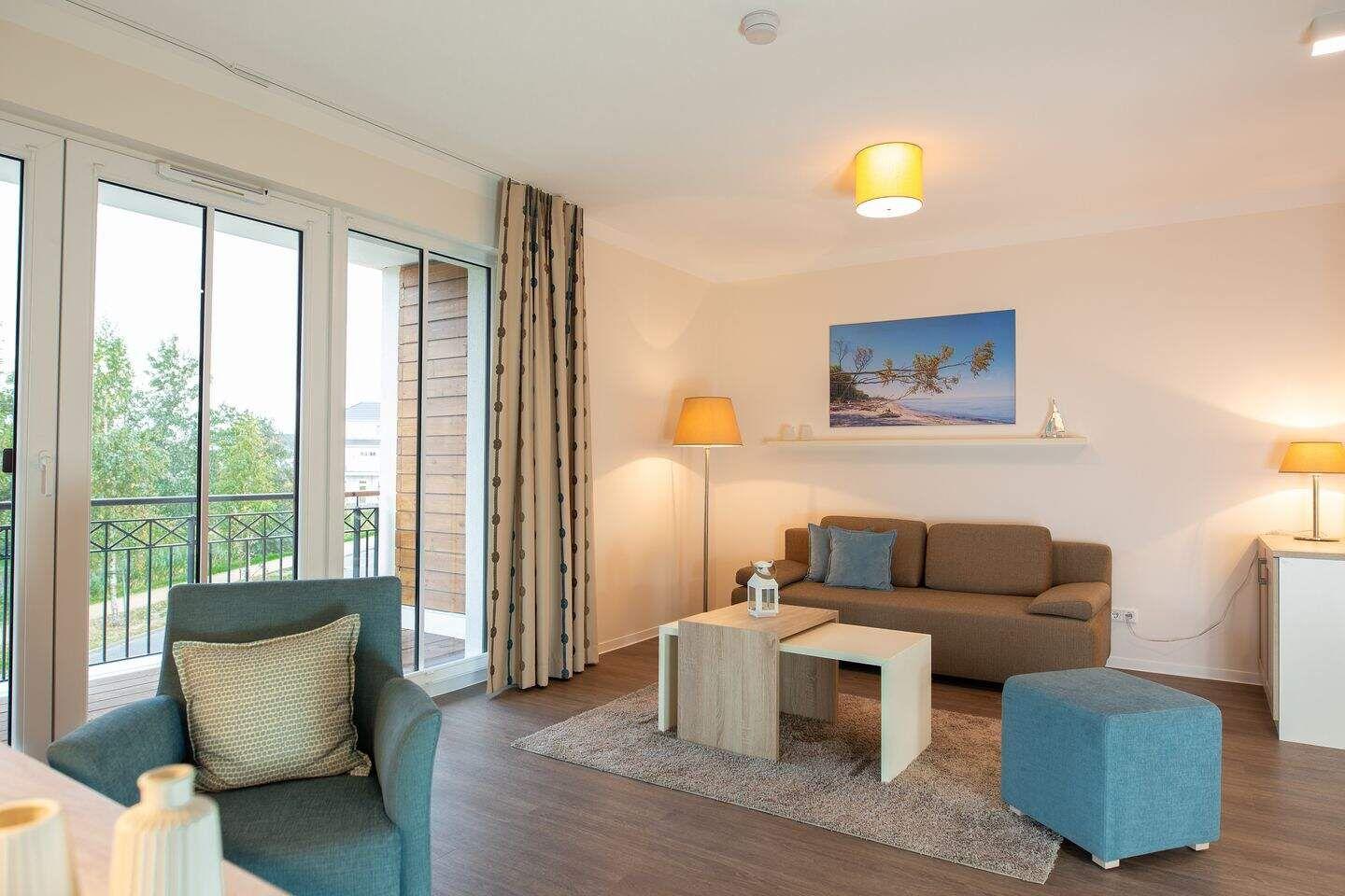Wohnzimmer mit Sofa, Sessel und Balkonansicht.