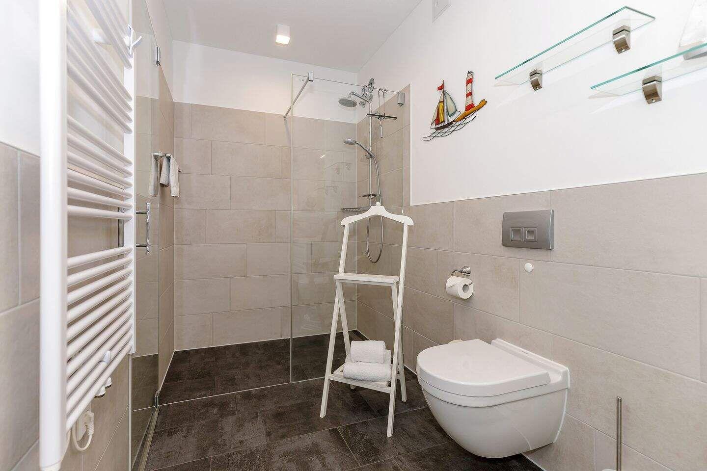 Badezimmer mit Dusche, Toilette und Heizkörper