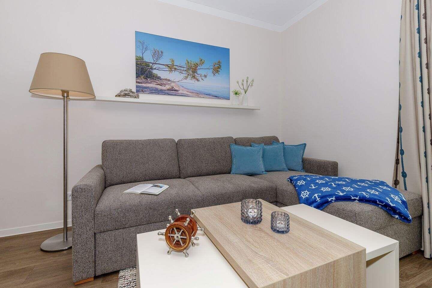 Ein Wohnzimmer mit grauem Sofa, blauen Kissen und einem Holztisch.