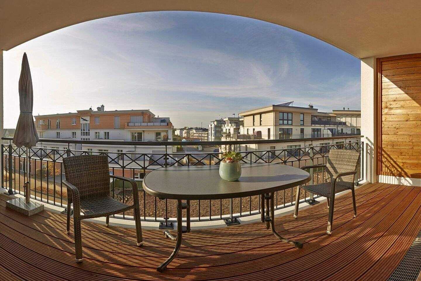 Terrasse mit Tisch, zwei Stühlen und Blick auf Wohngebäude.