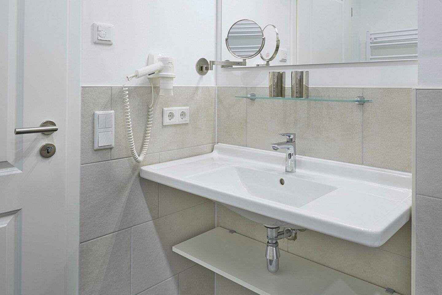 Badezimmer mit Waschbecken, Spiegel und Handtuchhalter
