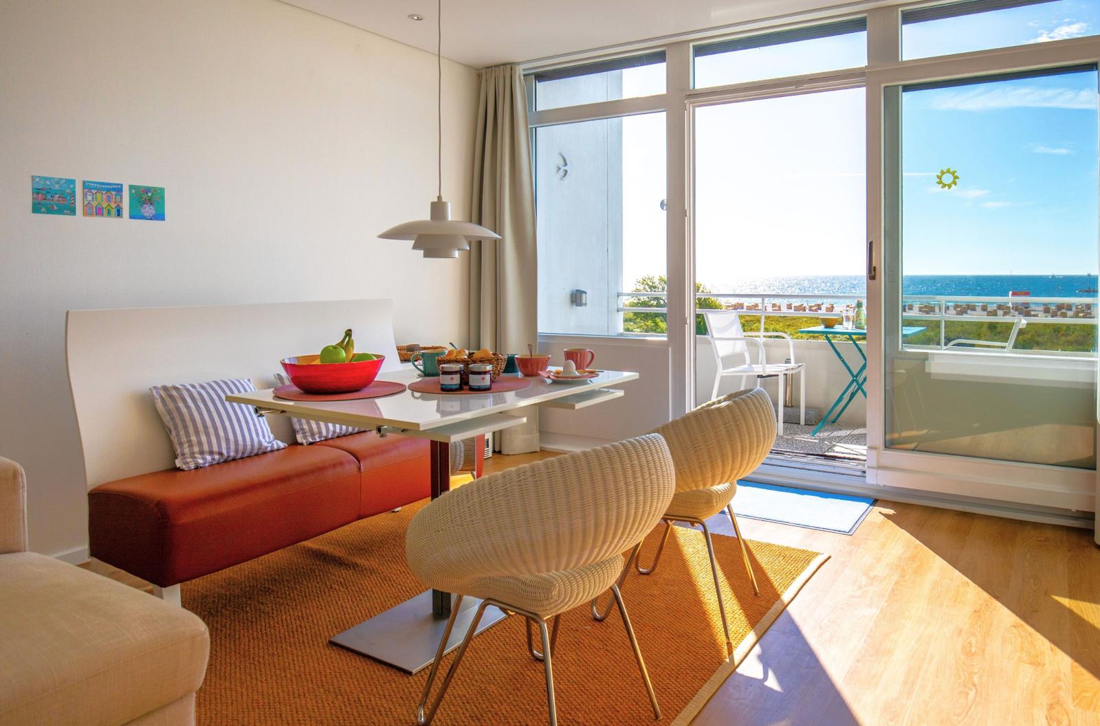 Essbereich mit Blick aufs Meer und Balkon mit Tisch und Stühlen.